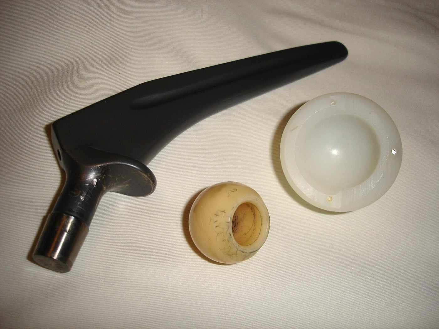 Figure 4. A disassembled hip prosthesis showing the bearing couple: femoral stem, head (with surface wear), and polyethylene cup. Source: Wikimedia Commons, public domain.