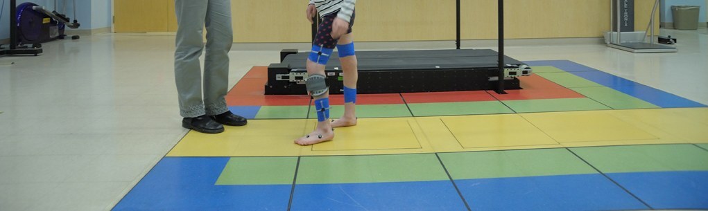 Instrumented gait analysis. A child with reflective/marker straps walks across the instrumented walkway of a motion-analysis laboratory, generating the kinematic, kinetic and dynamic-EMG data used to plan multilevel surgery. NIH Clinical Center (public domain), via Wikimedia Commons.