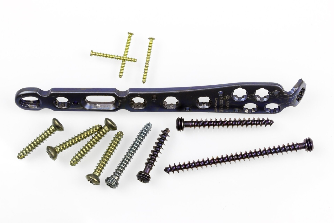 Figure 1. An assortment of osteosynthesis hardware: an angular-stable (locking) plate with combination holes and a range of cortical and locking screws. Source: Superbass, via Wikimedia Commons, CC BY-SA 4.0.